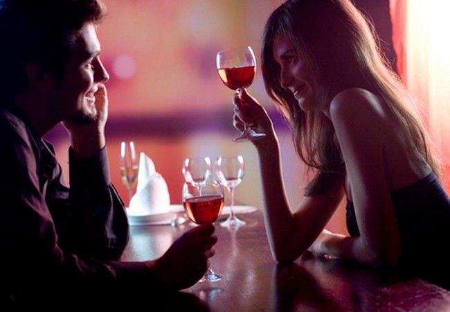 Young couple sharing a glass of red wine in restaurant, celebrat